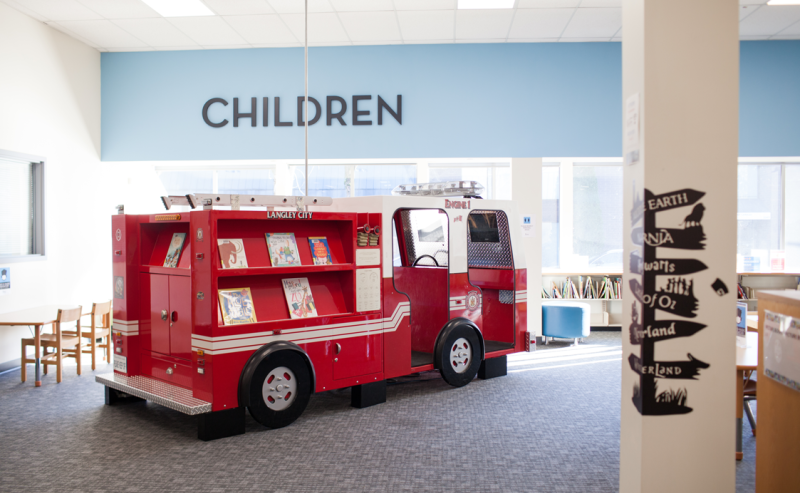 A bright red fire truck sits in the City of Langley Library, inviting young readers to explore and enjoy storytime.