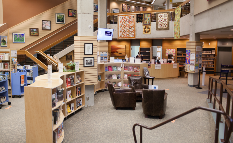 Inside White Rock Library, a spacious area filled with books and inviting seating for customers near the information desk.