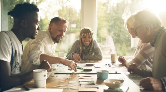 A diverse group of friends gathered around a table, enjoying a lively board game night together.