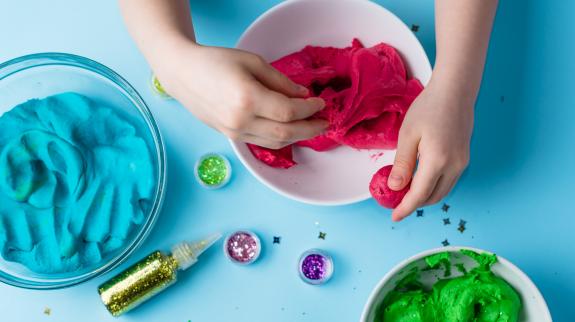 A child's hands knead vibrant play dough, creating colorful shapes and textures in a fun, creative activity.