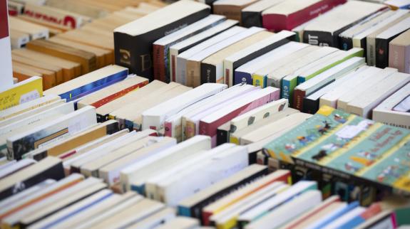 Books stacked on their sides on a table to be sold at a library booksale.