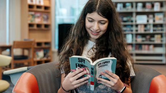 A teen girl reads a book at Maple Ridge Public Library.