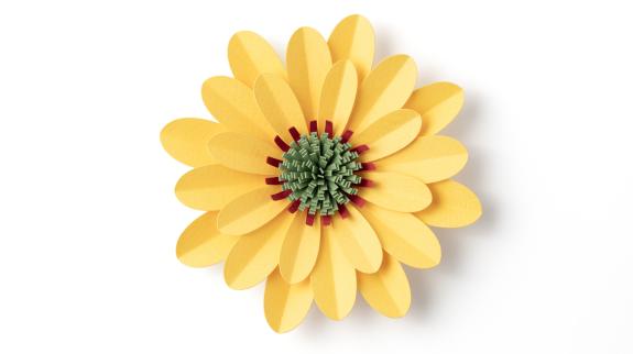 Handmade yellow flower with purple and green centre on white background.