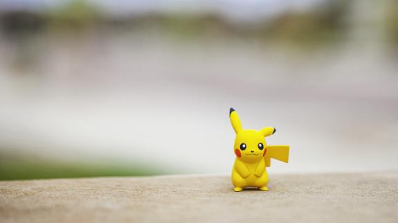 Pokemon Go character Pikachu, standing on top of a wall outdoors, in front of a defocused street.