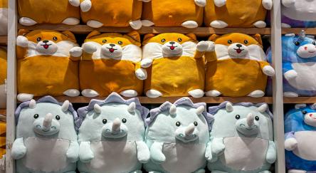 A charming display of various stuffed animals, known as Squishmallows, lined up on multiple shelves.