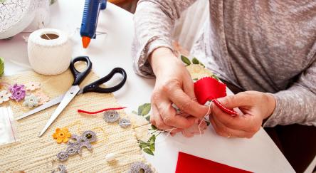 Senior women sews by hand and making heart shape ornament.