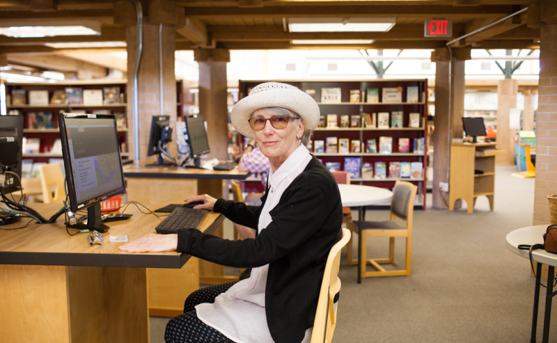 A woman with a hat relaxes in the Ladner Pioneer Library, immersed in the inviting atmosphere of the public computer area.