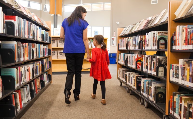 Inside Sardis Library, a woman and a little girl share a moment among the bookshelves, enjoying their time together.