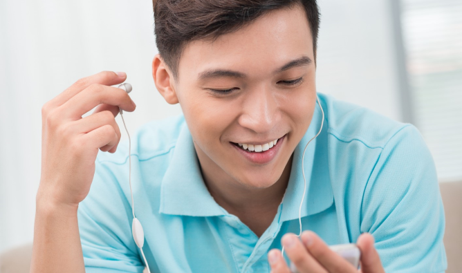 A young man is listening to a podcast on his earphones.