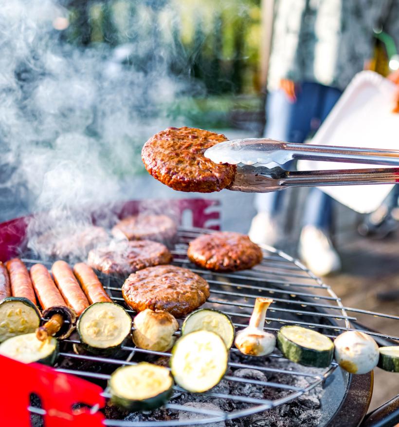 Burgers, hot dogs and vegetables sizzle on a backyard grill.